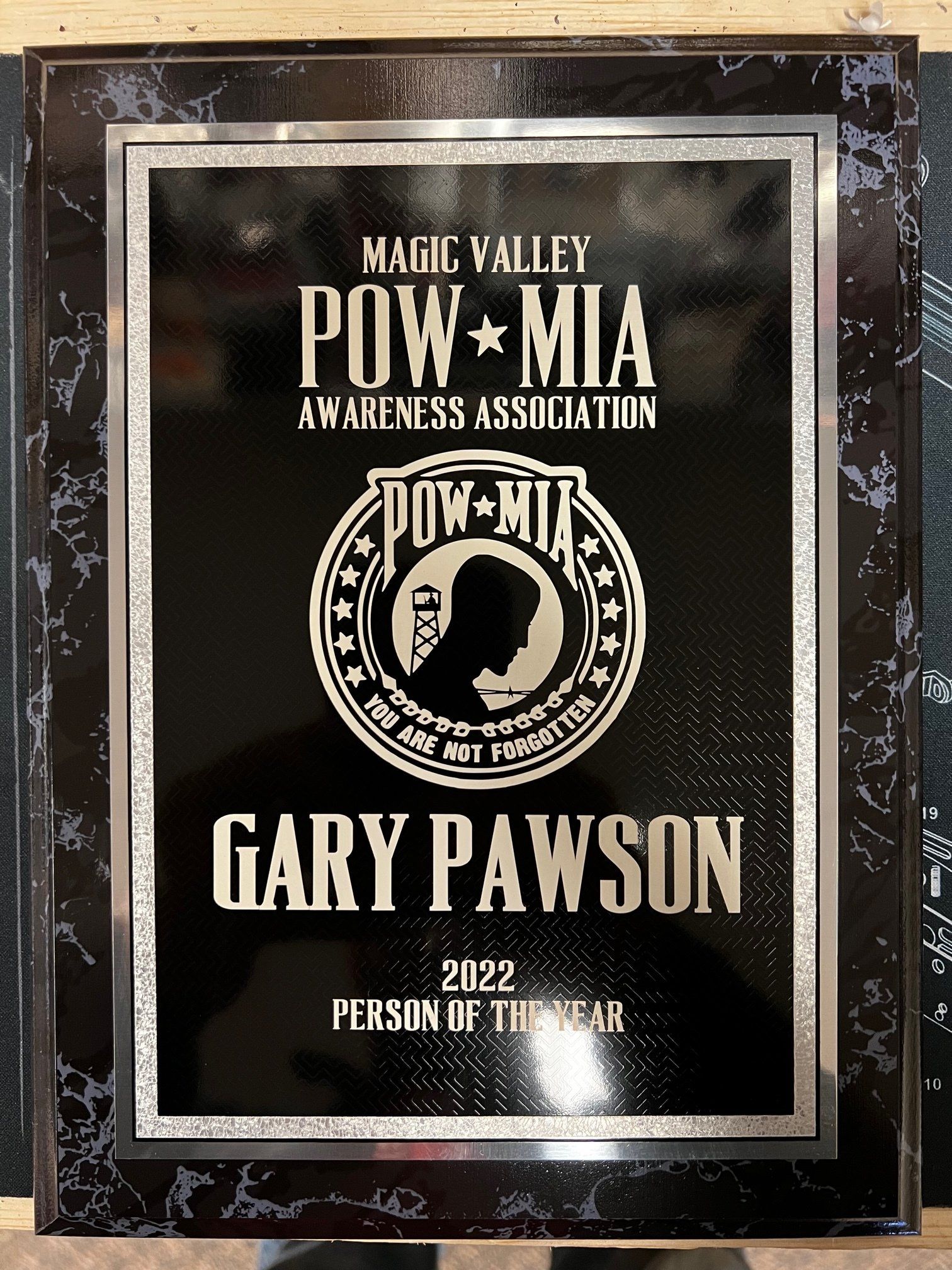 Plaque honoring Gary Pawson as 2022 Person of the Year by Magic Valley POW-MIA Awareness Association. Black, silver design.