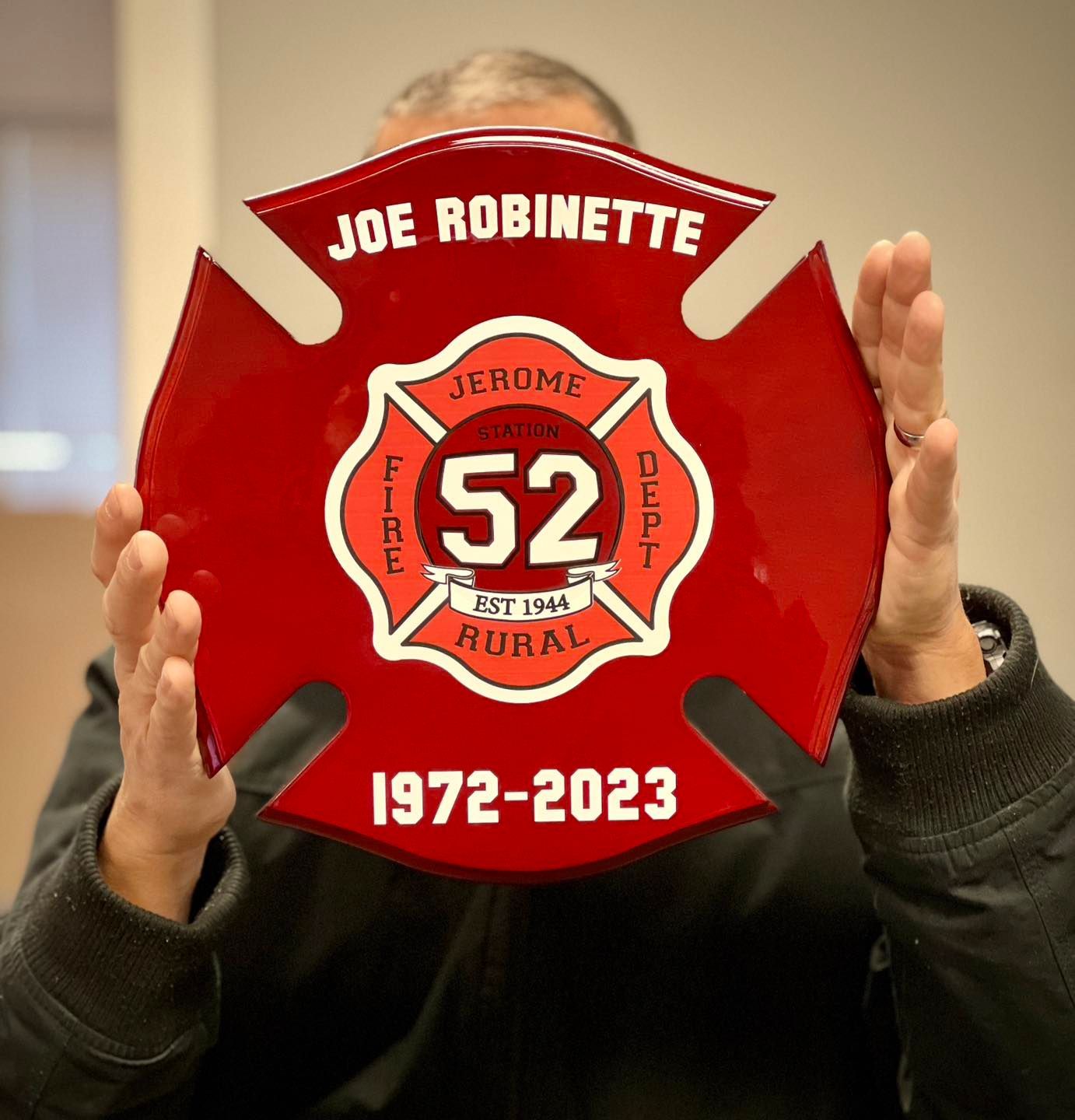 Person holding a red firefighter's cross with 