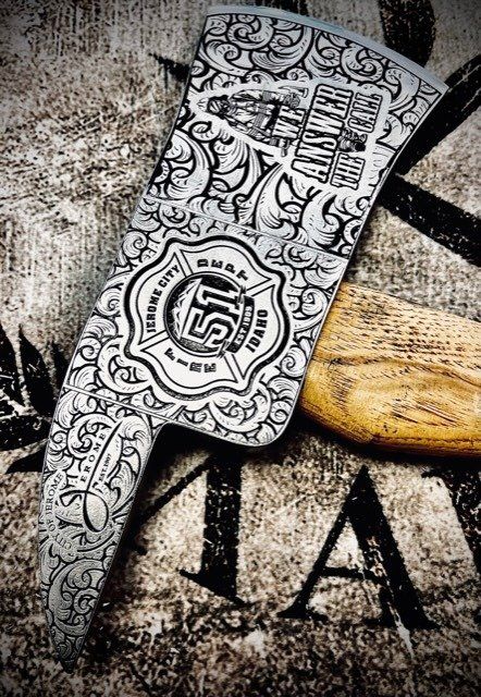 Black-and-white ornate knife with a patterned blade and wooden handle on textured fabric and leather background
