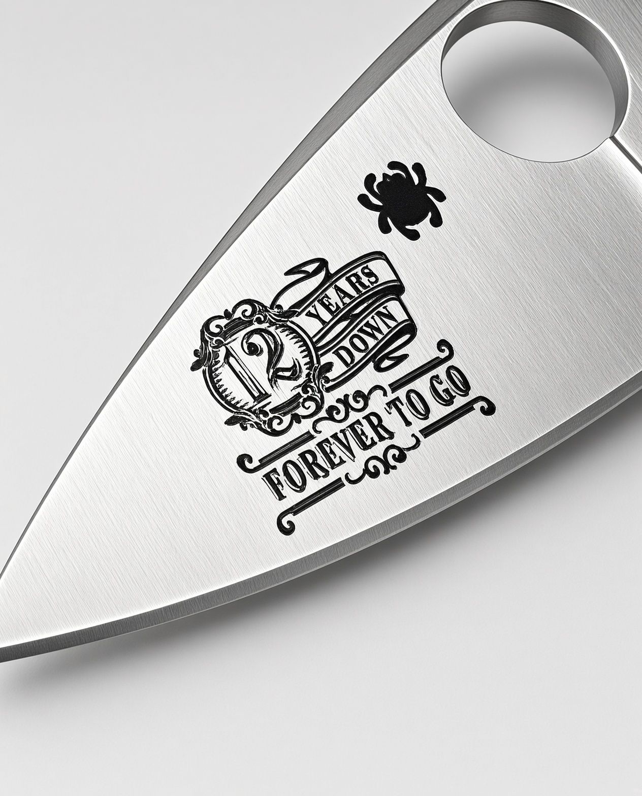Close-up of a metal knife blade with a stamped logo and text on a white surface.