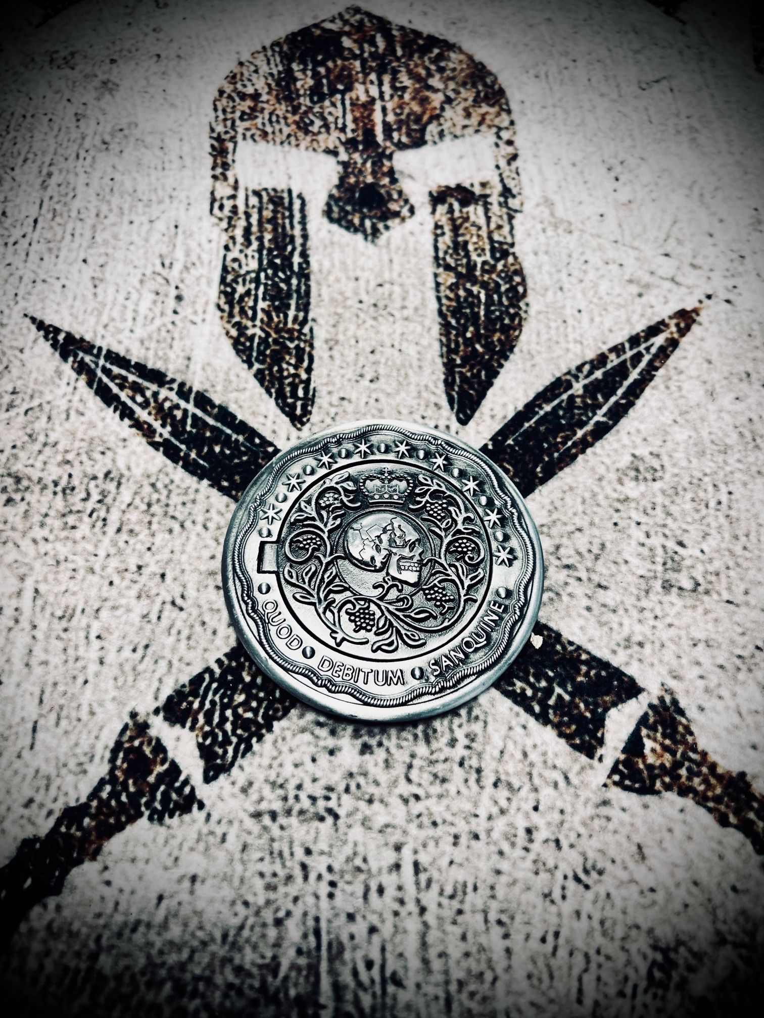 Spartan helmet and crossed swords stencil with a silver coin at the center.