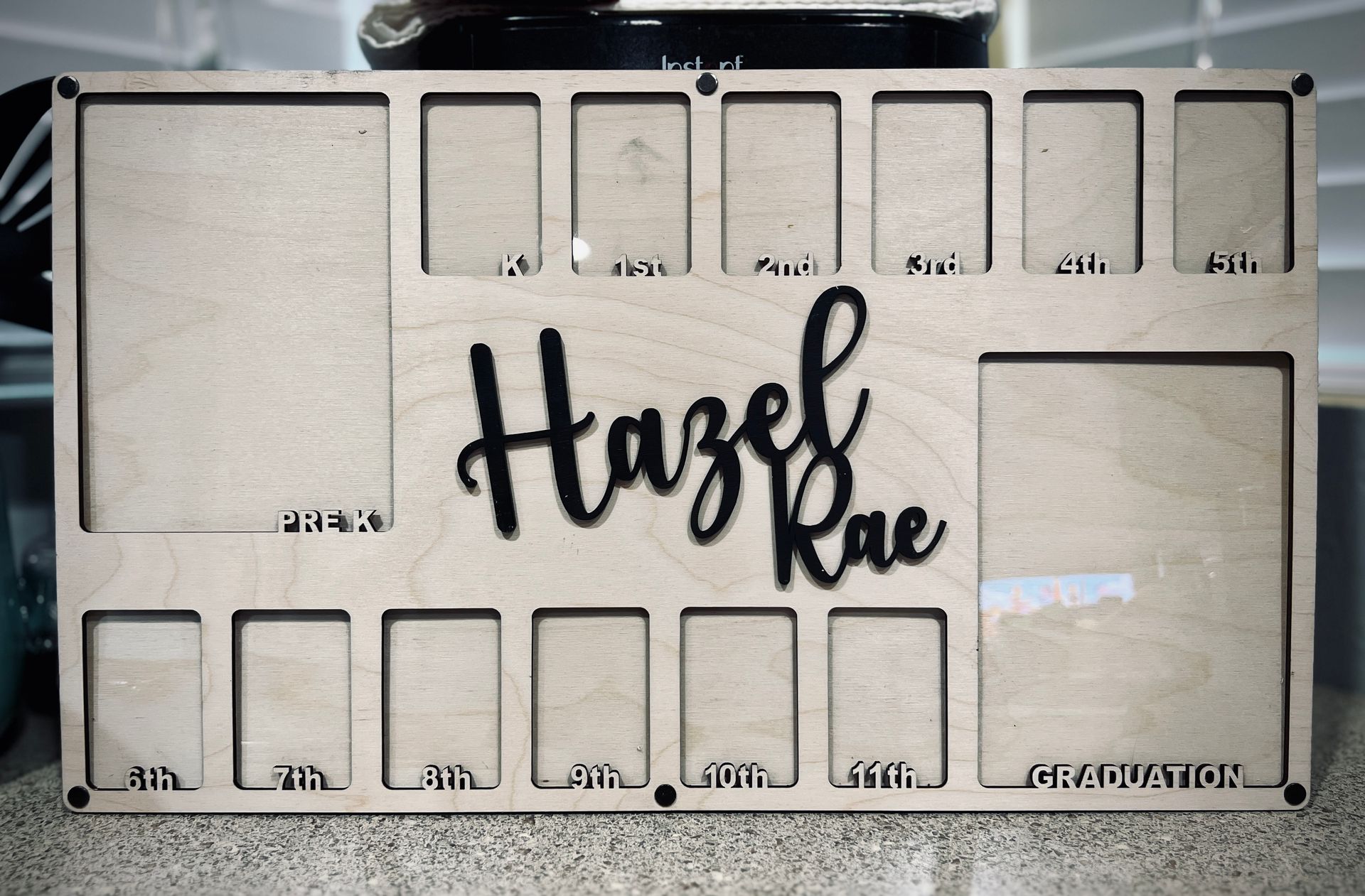 Custom wooden board with engraved name “Hazel Rae” and multiple labeled photo slots.