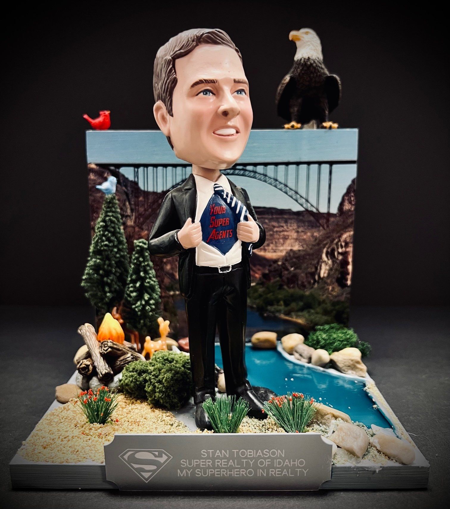 Bobblehead of Stan, superhero-themed, with a scenic background and an eagle on top.