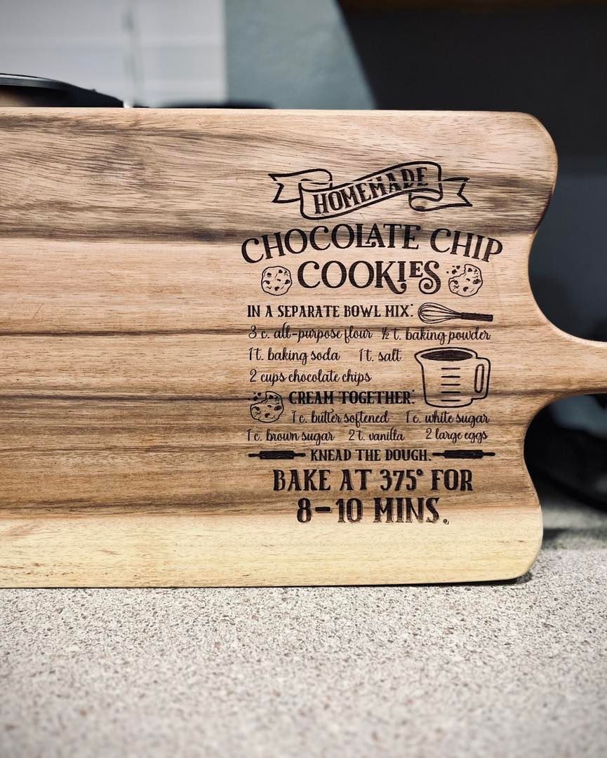 Wooden cutting board with etched recipe for homemade chocolate chip cookies.