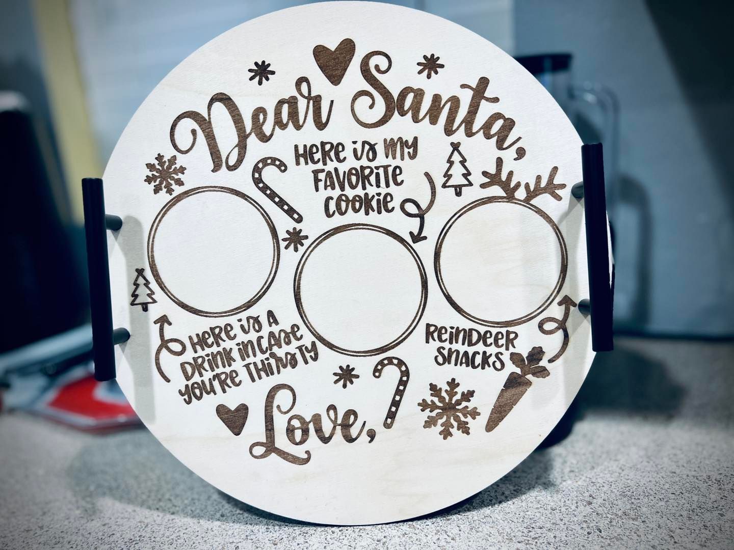 White Santa-themed wooden sign with three blank ornament circles and holiday text on a countertop