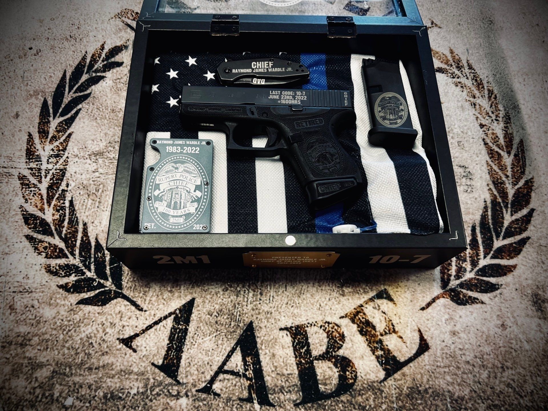 Wooden box with a handgun, knife, flag, and other law enforcement items.