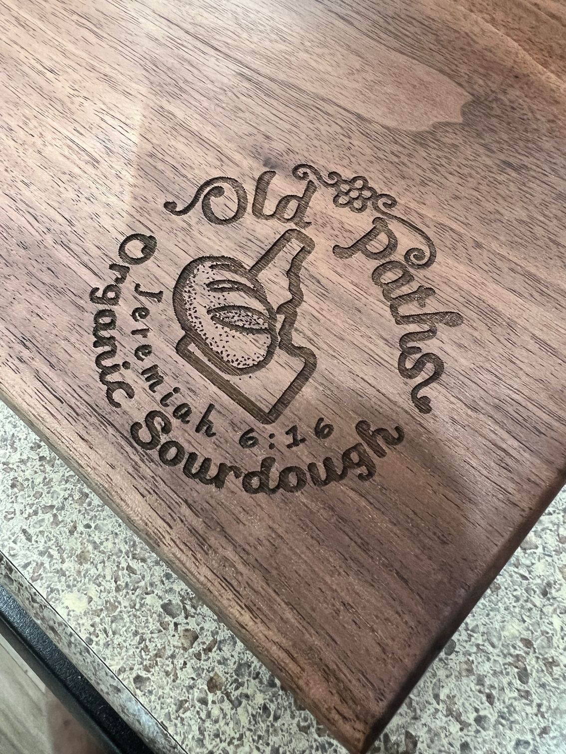 Wooden plaque with a burned logo reading “Olde Town Public House & Souvenirs” on a speckled countertop