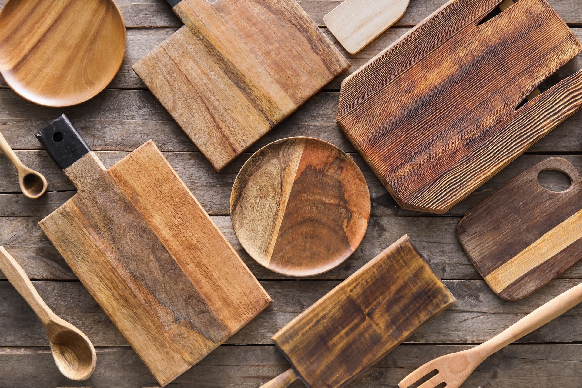 Assorted wooden cutting boards and kitchen utensils on a gray stone surface