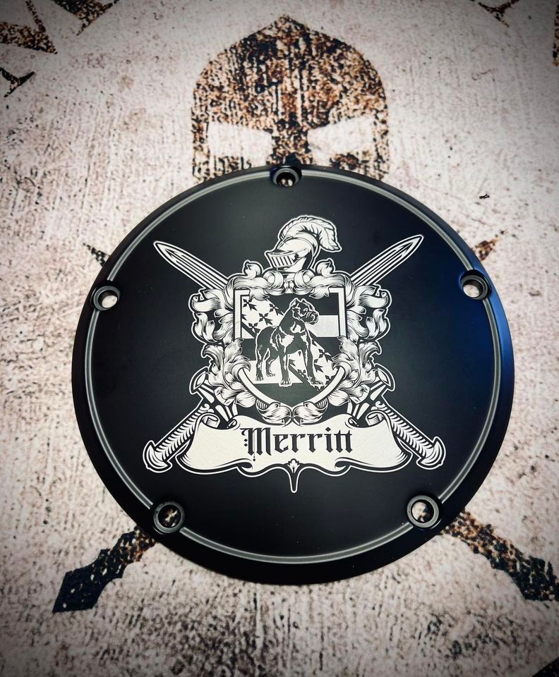 Black, circular cover with a crest design, the word 