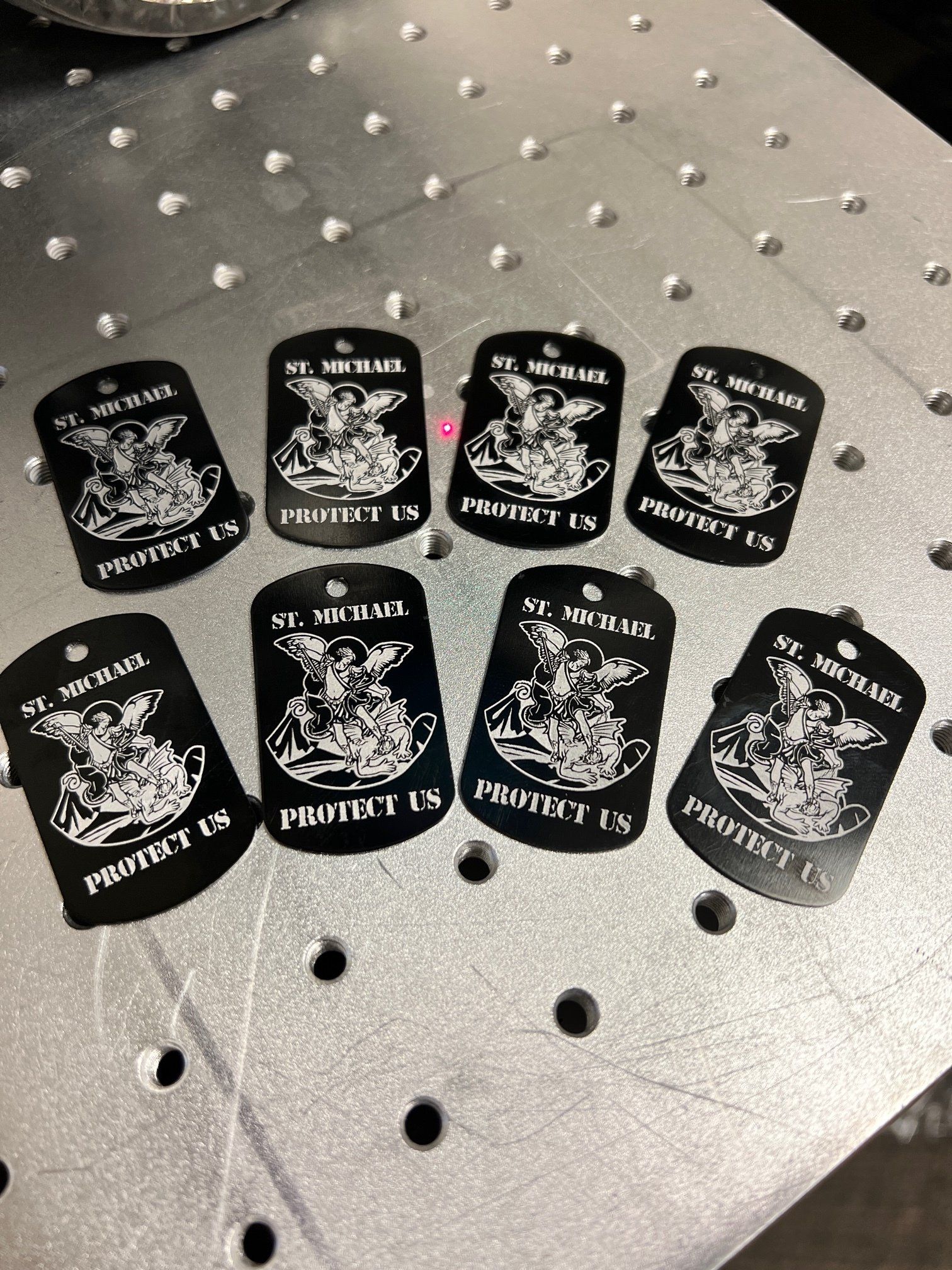 Eight black dog tags with laser-engraved image of St. Michael and 