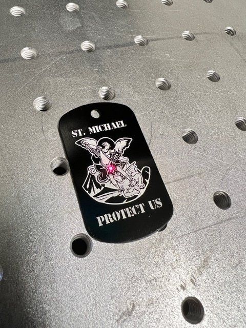 Black dog tag engraved with St. Michael and the words 