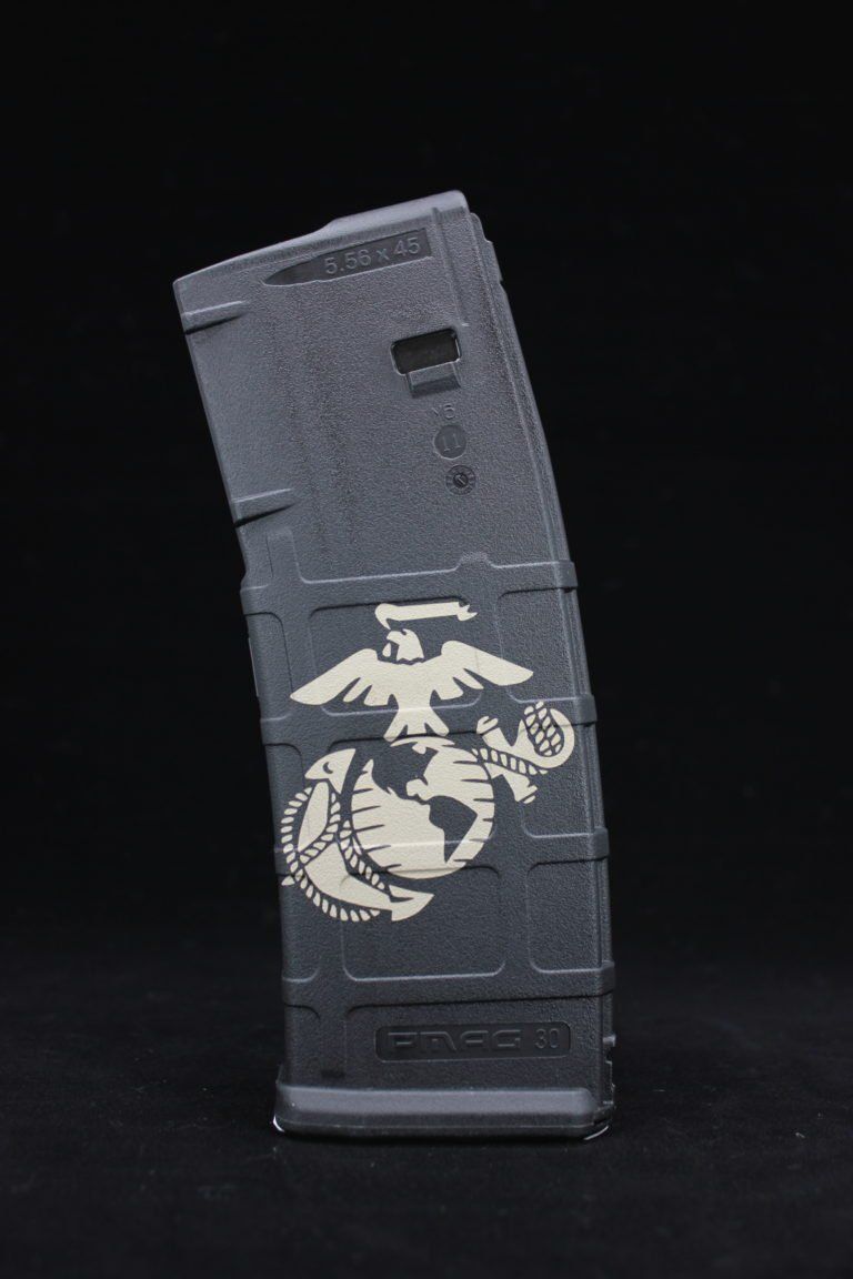 Gray rifle magazine with a white U.S. Marine Corps emblem on a black background