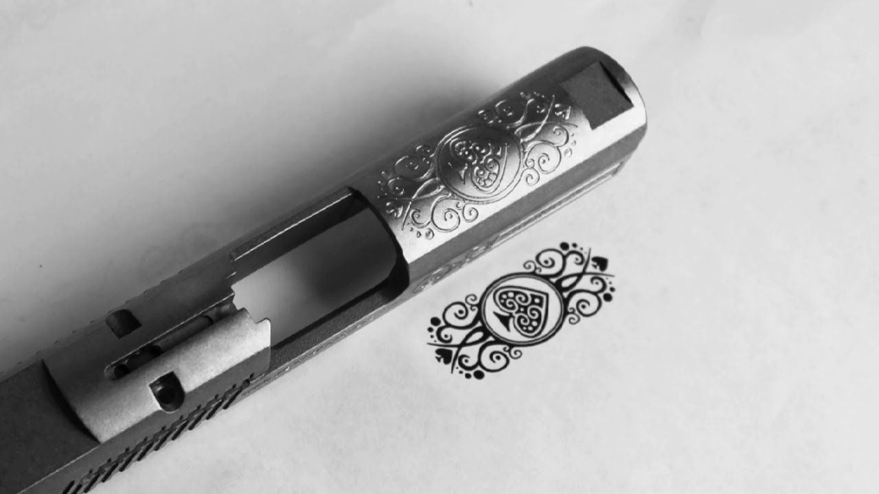 Close-up of a metal drill or screwdriver bit on a white surface beside a decorative emblem.