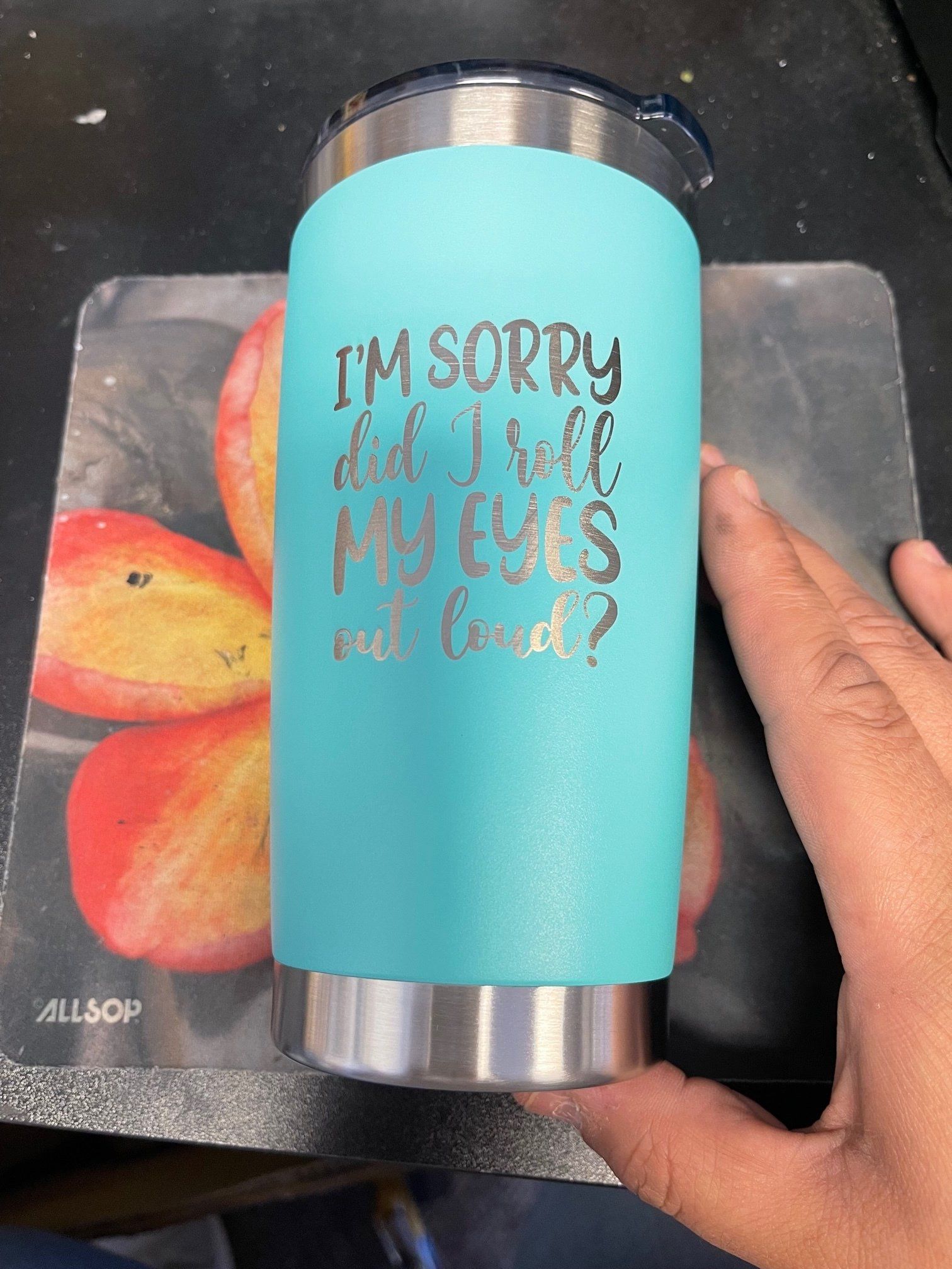 Turquoise tumbler with “I’m sorry for what I said when my eyes were closed” quote, held over a colorful coaster.
