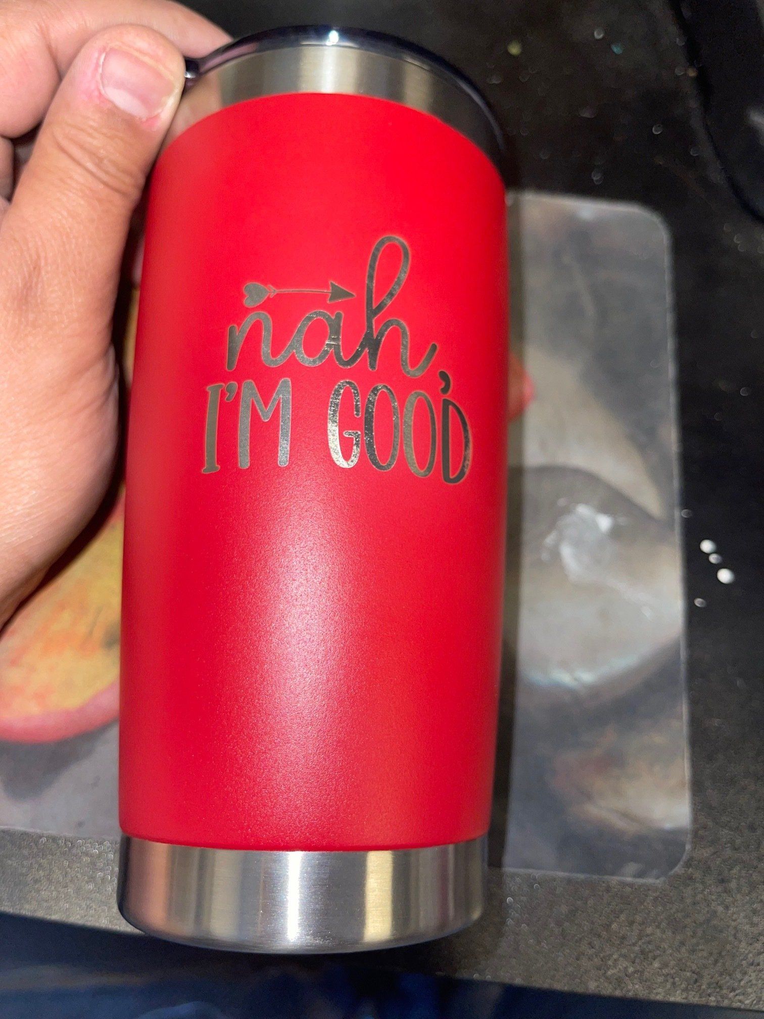 Red tumbler with black lid and base, held in a hand, printed with “nah, I’m good.”