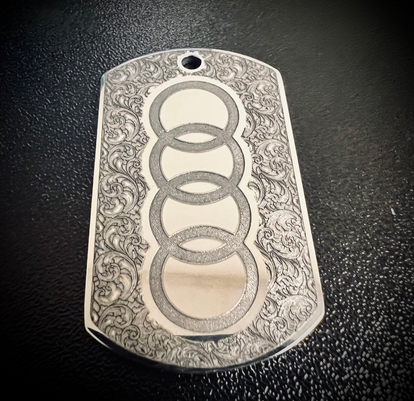Silver engraved dog tag with Audi logo and floral design.
