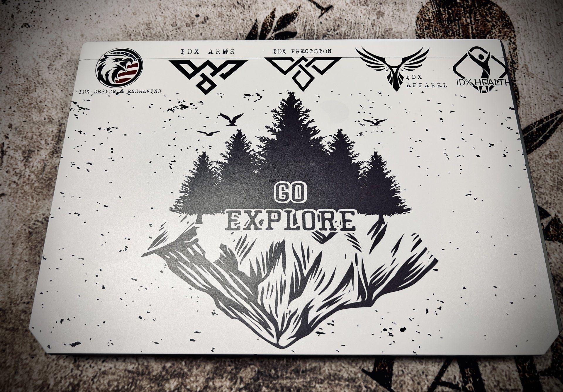 Laptop with a mountain and forest graphic that says 