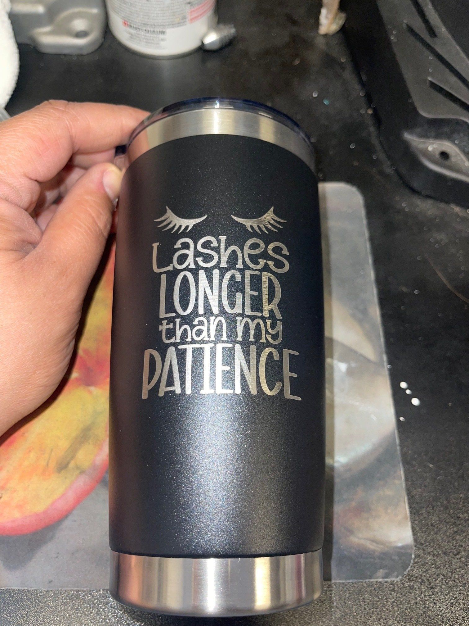 Black tumbler with silver top and bottom, reading “Lashes longer than my patience.”