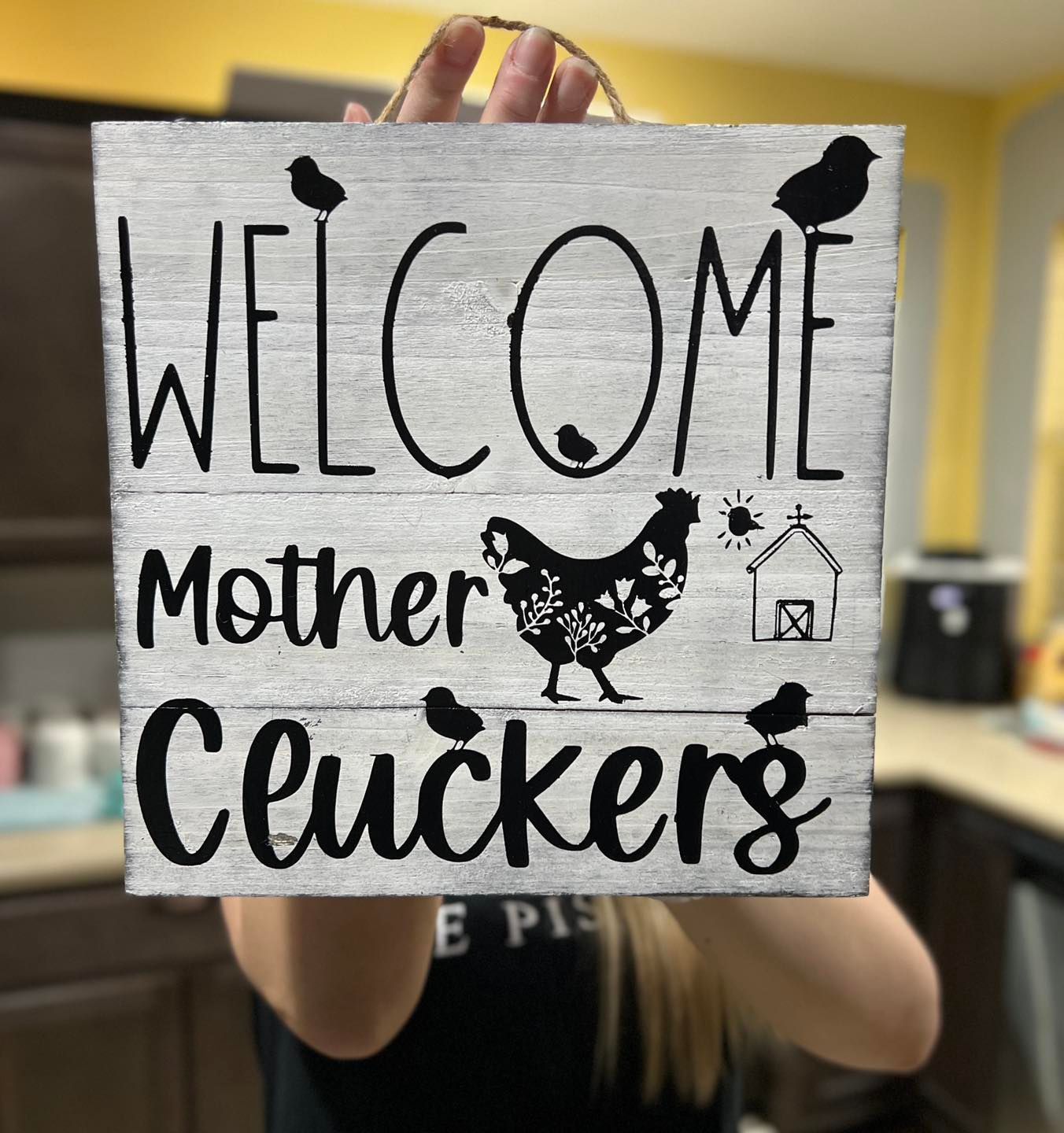 Handmade sign reading “WELCOME Mother cluckers” with a chicken illustration and paw prints