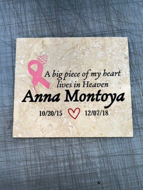 Memorial plaque reading “A big piece of my heart lives in Heaven” for Anna Montoya, with pink ribbon and dates.