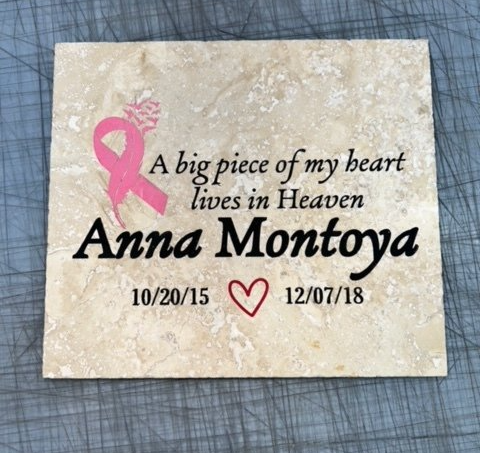 Memorial stone for Anna Montoya, with a pink cancer ribbon and dates 10/20/15 - 12/07/18. Text reads: 