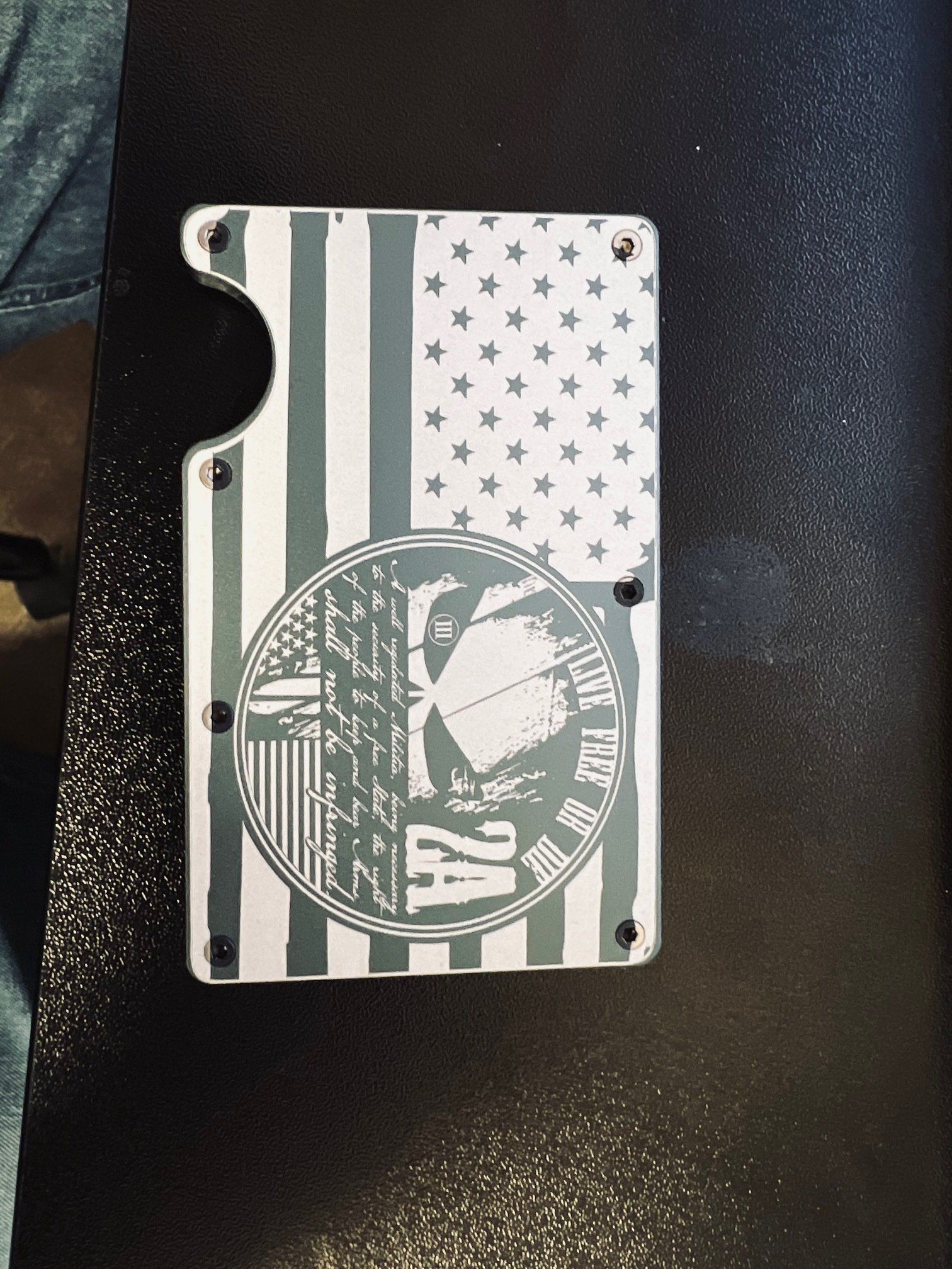 Metal wallet with an American flag design and a circular emblem on a dark textured surface