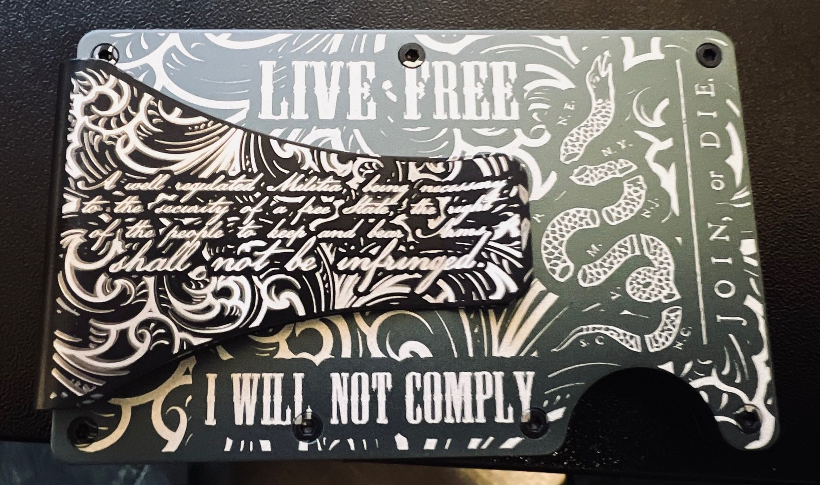 Gray metal wallet with etched text: 