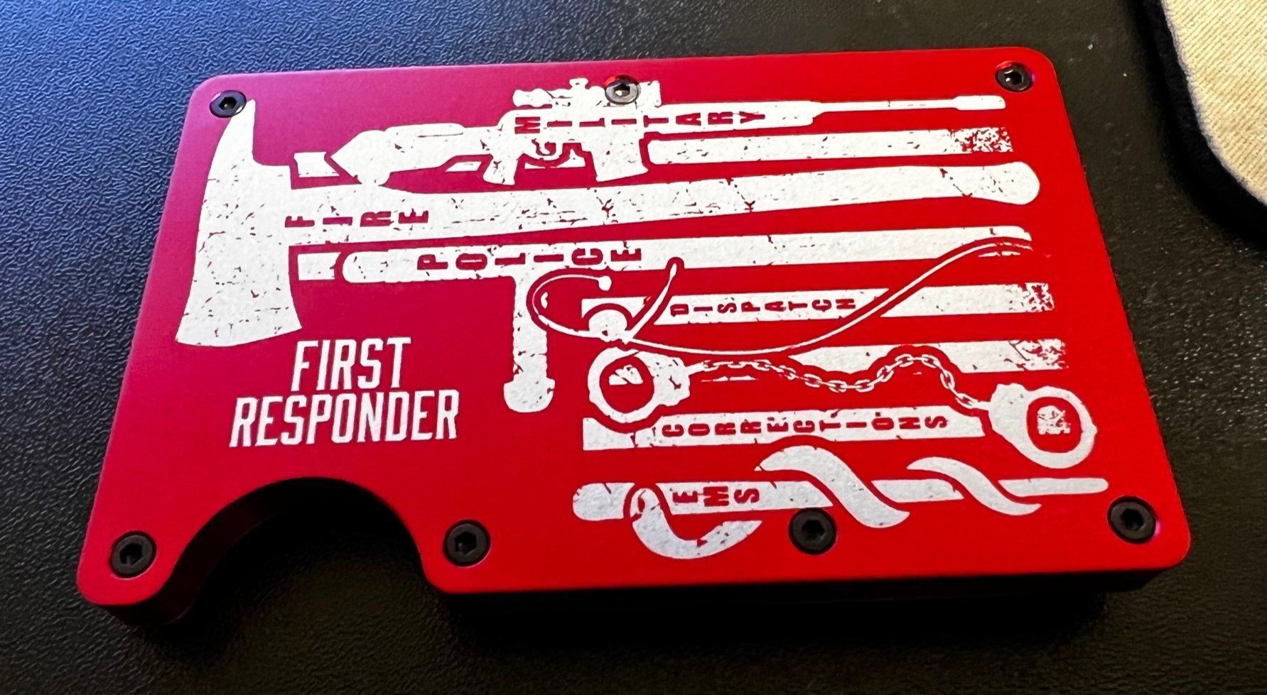 Red first responder plaque with white emergency vehicle silhouettes and text on a black surface
