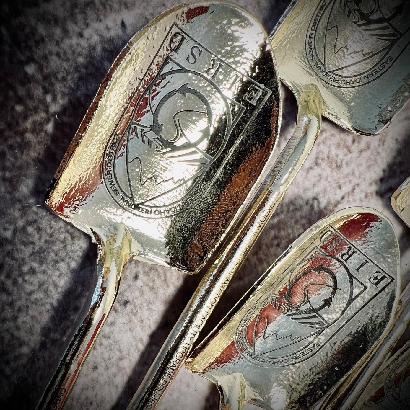 Silver miniature shovels with a logo of a mountain and text.