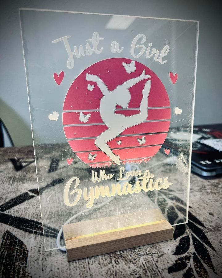Illuminated gymnastics sign: Girl silhouette in front of red sunset, with text 