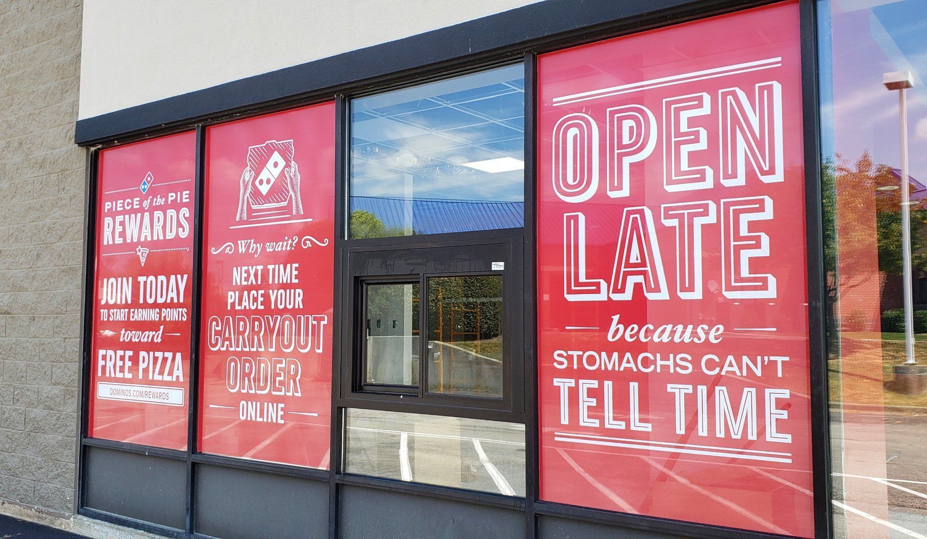 Storefront with red promotional signs and a large “OPEN LATE” window display.