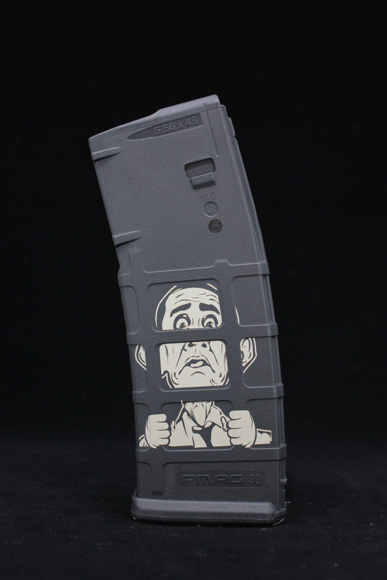 Black gun magazine with a distressed face design behind prison bars.