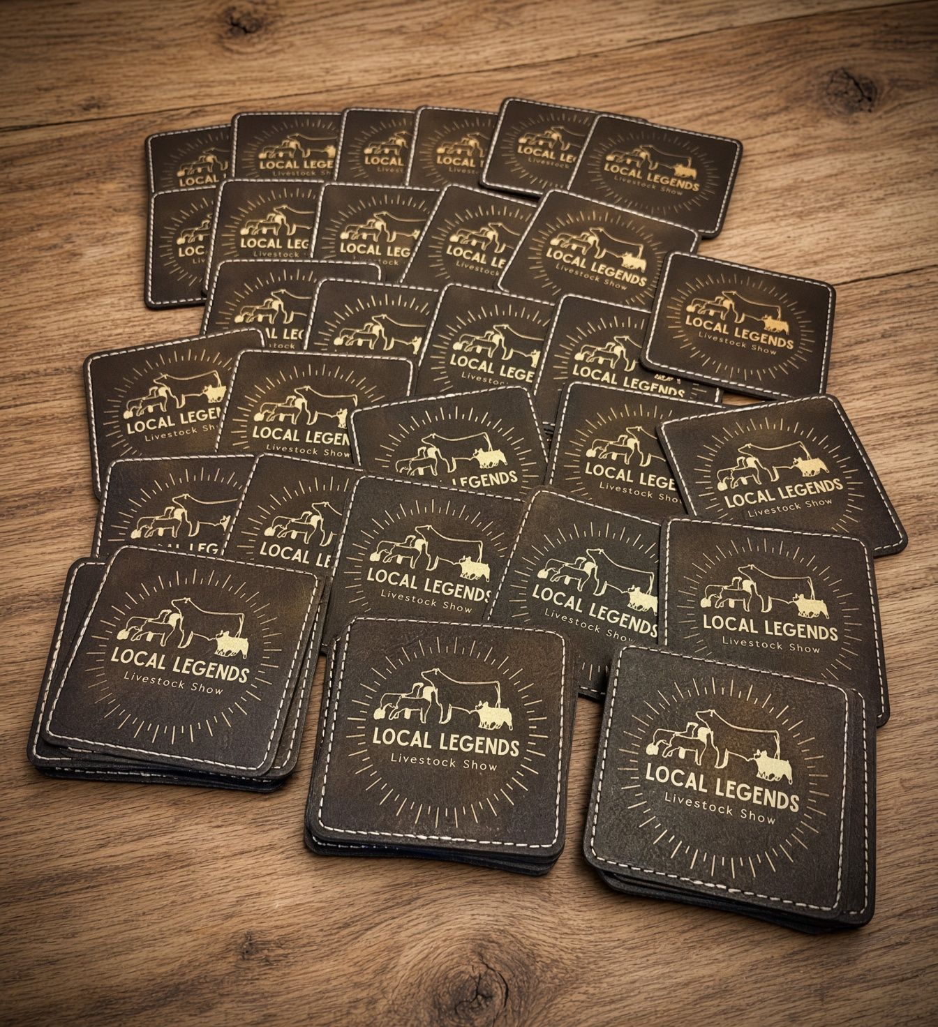Stack of dark brown leather-bound books spread on a light floor, with gold lettering on the covers