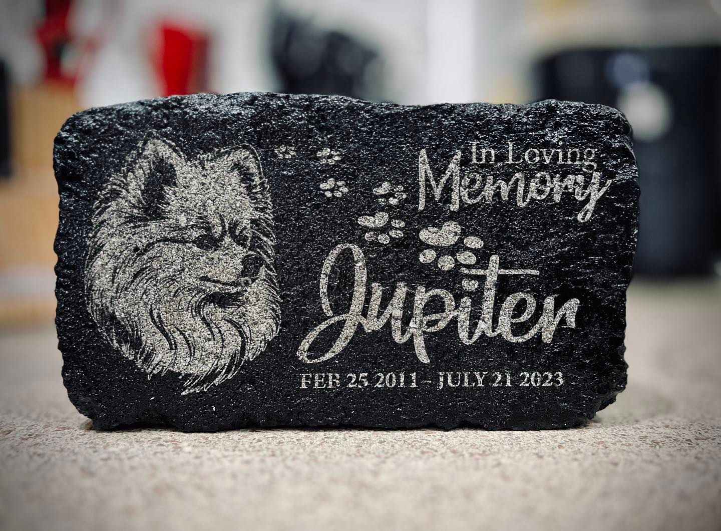 Black stone pet memorial for a dog, with an engraved portrait of a dog and the inscription, 