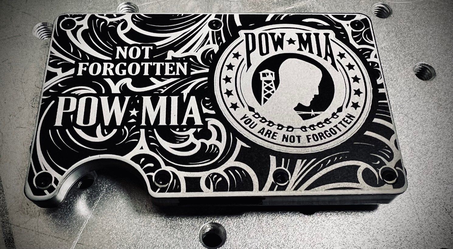 Black-and-white POW/MIA memorial graphic on a rectangular object with skull and eagle emblem, resting on a textured surface