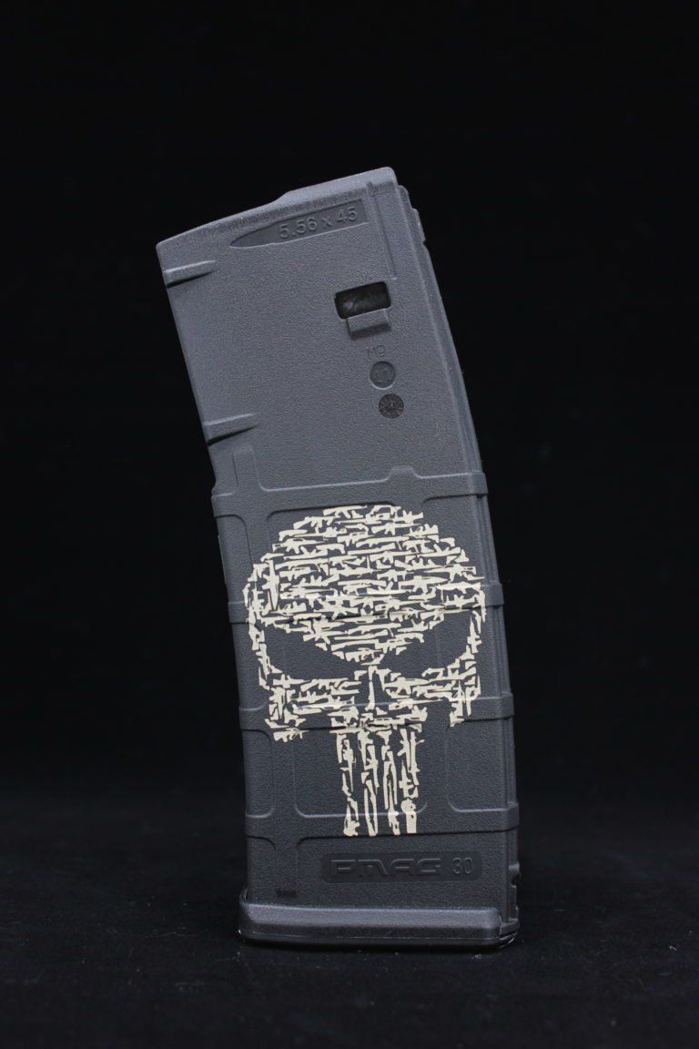 Gray gun-shaped device with a white skull emblem on a black background