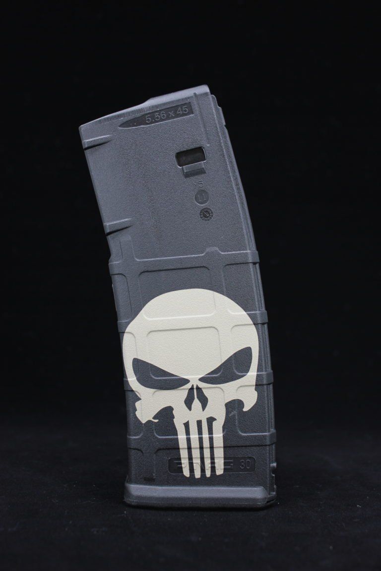 Gray firearm magazine with a white skull emblem on a black background