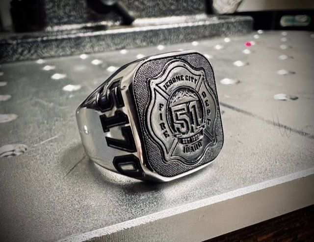 Silver championship ring with a large “51” emblem resting on a gray tabletop, with blurred lights in the background