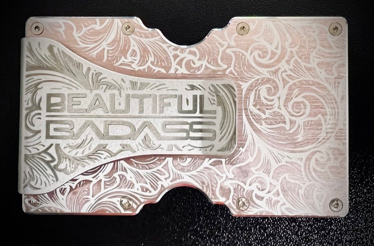 Pink engraved metal plaque reading “Beautiful Badass” on a black background