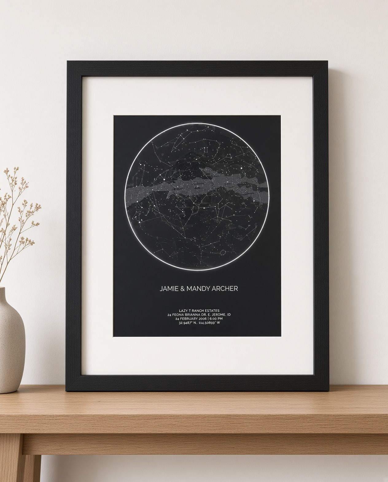 Framed black poster with a circular star map and white matting on a wall.