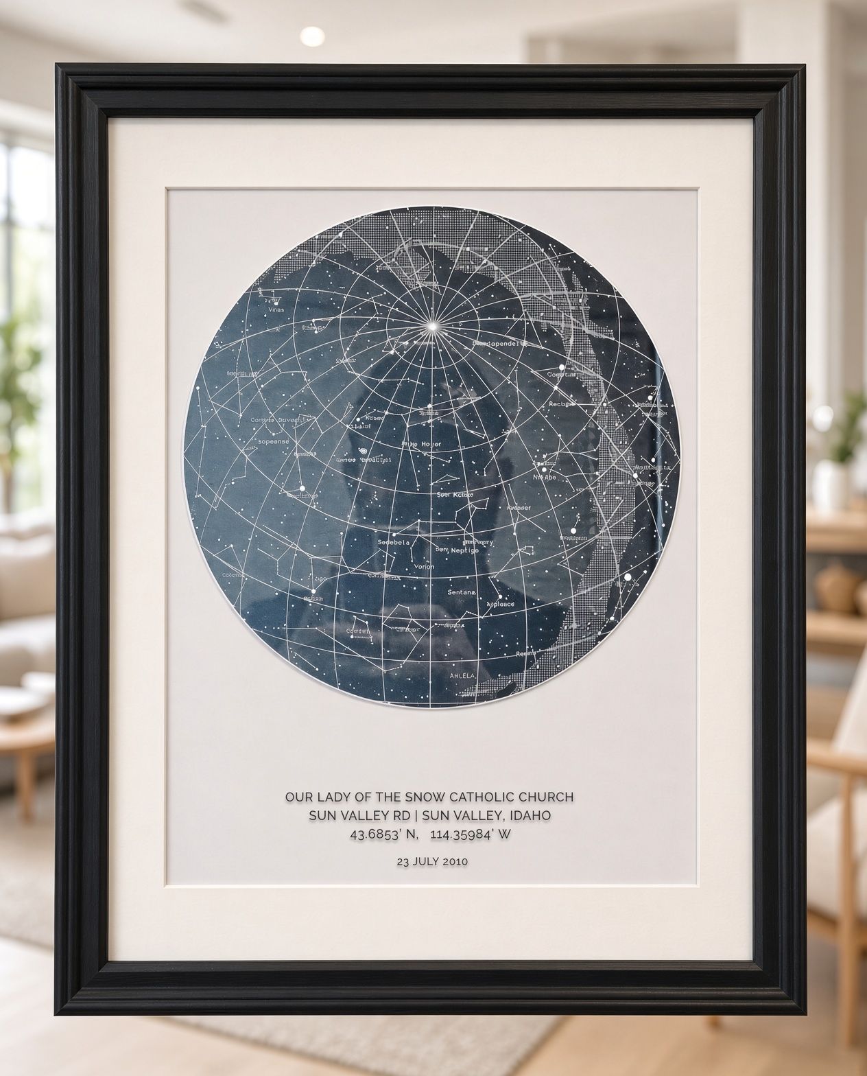 Framed circular star map print with white mat, held up against a dark red wall.