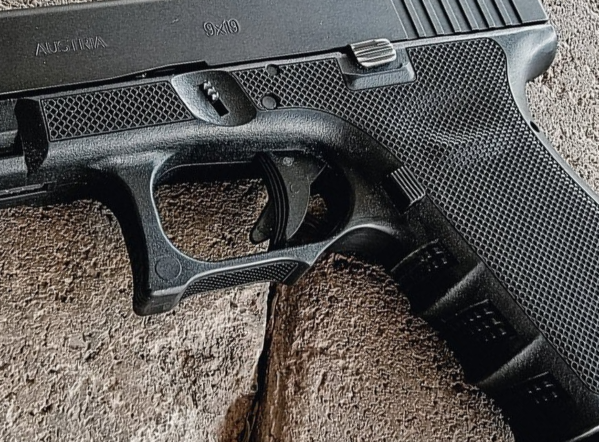 Close-up of a black handgun resting on a rough surface.