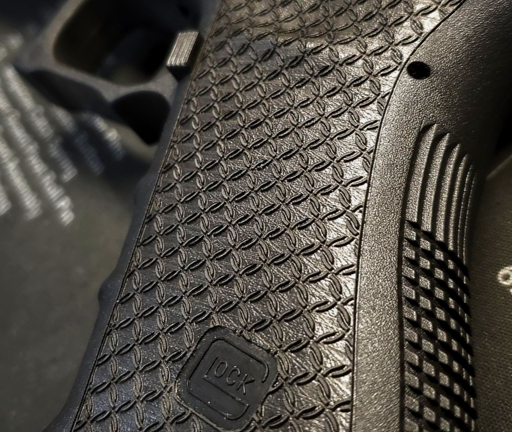 Close-up of a black textured handgun grip with a small logo visible