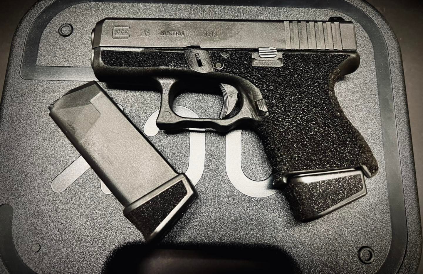 Black handgun and magazine in a foam-lined gun case