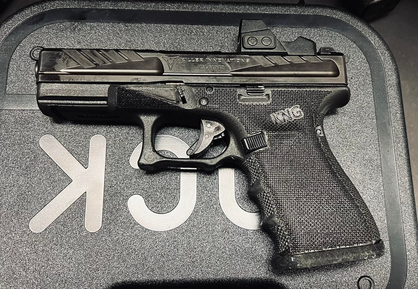 Black handgun in a foam case on a black surface with white lettering
