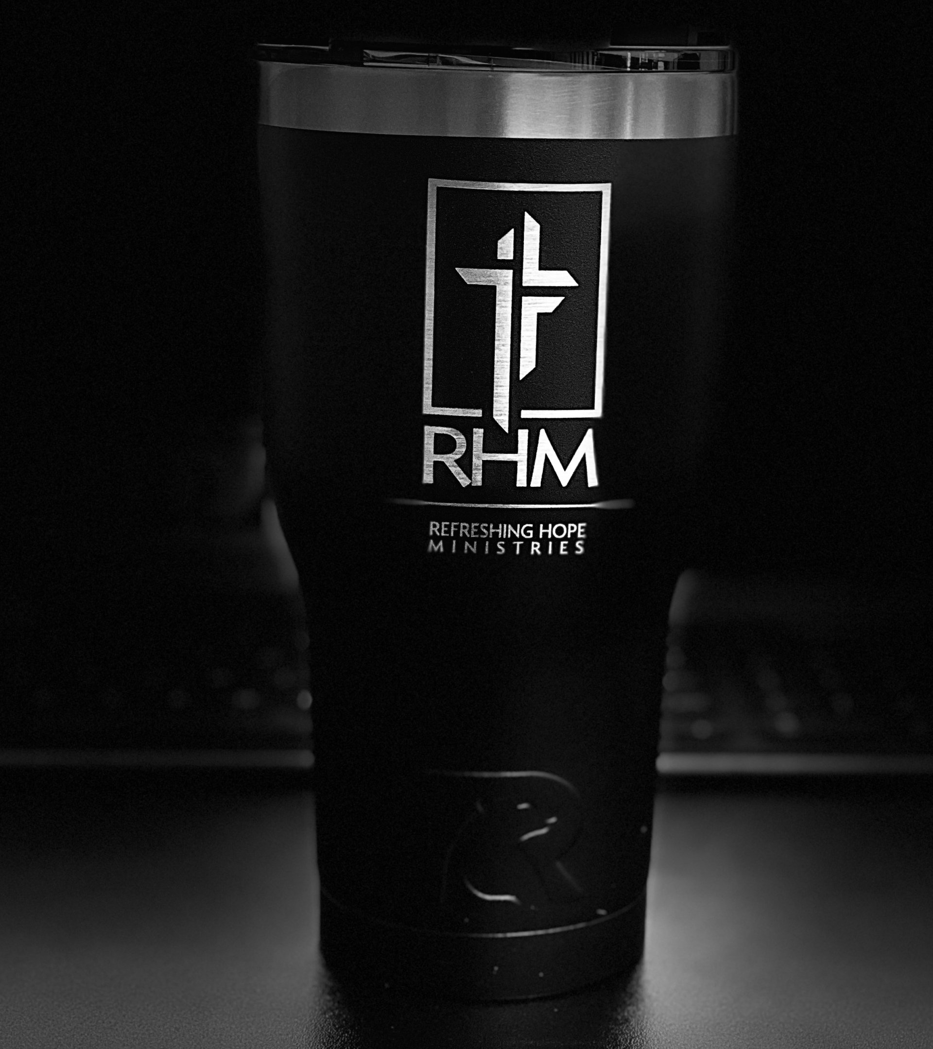 Black tumbler with a logo featuring a cross and the initials 