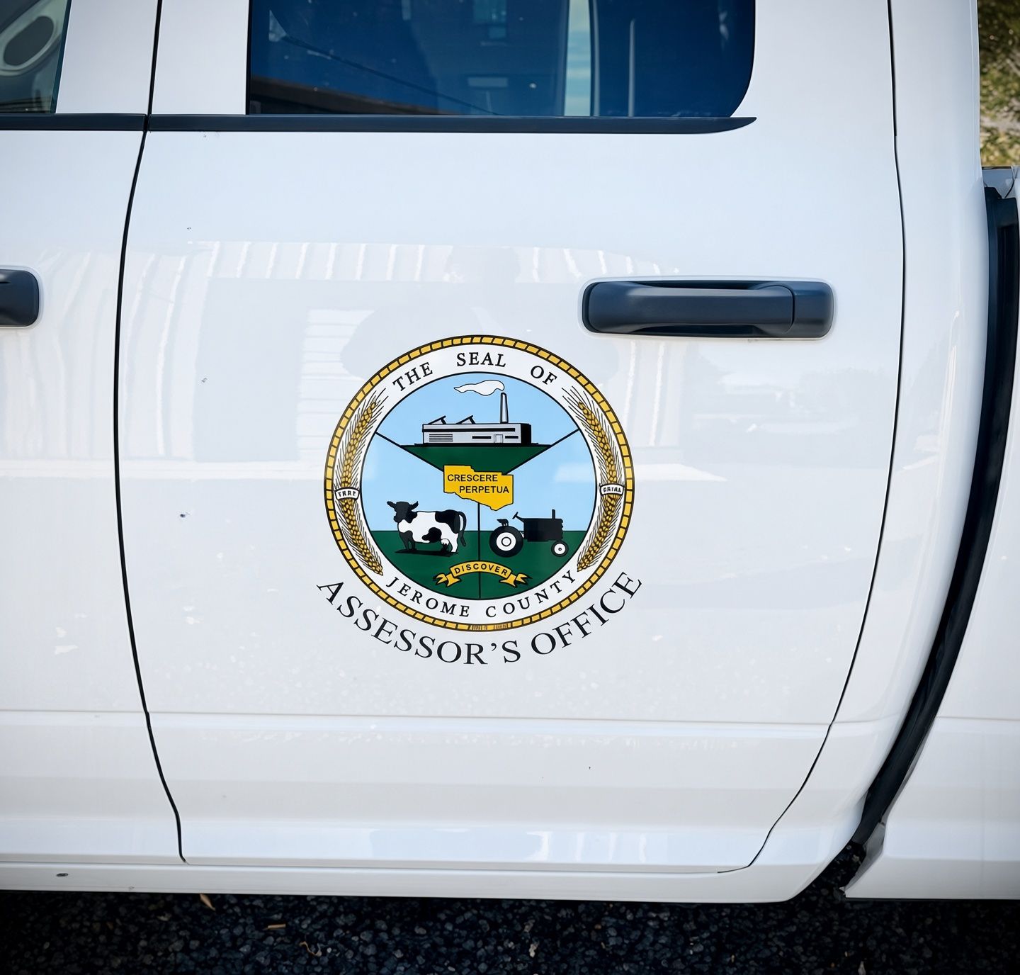 Close-up of a white truck door with the Assessor's Office seal and black handle.