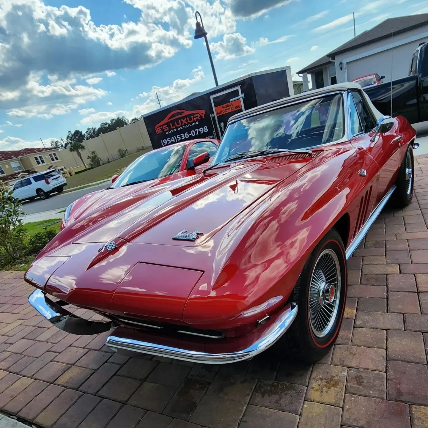 Red vintage Corvette convertible parked on brick.