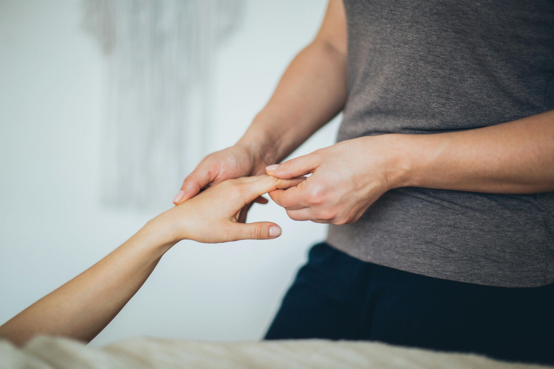 Person's hands receiving gentle hand massage. Light skin tones, indoor setting.