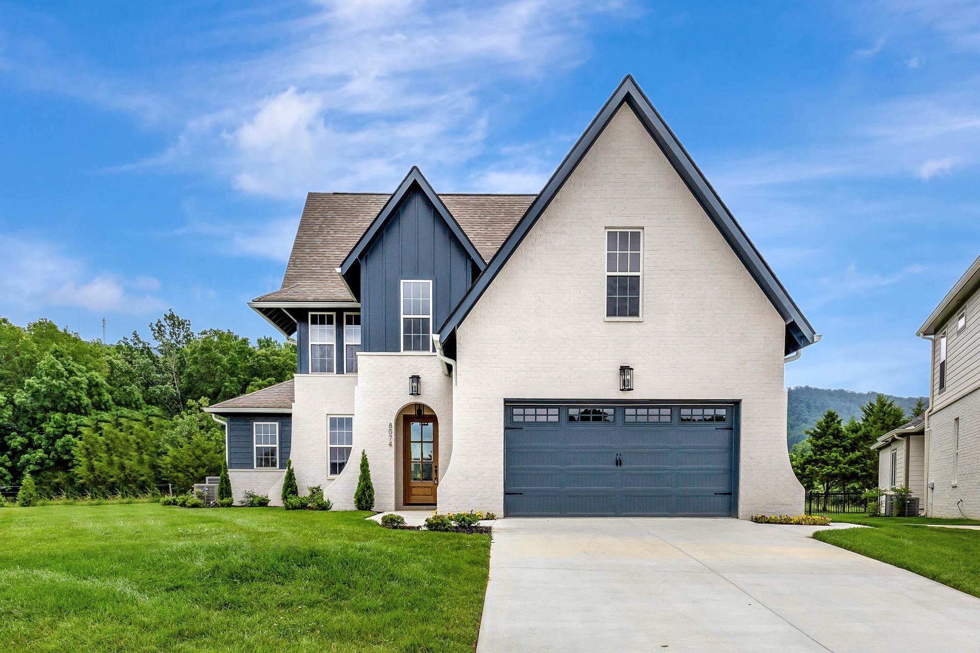A large white house with a blue roof and a black garage door.